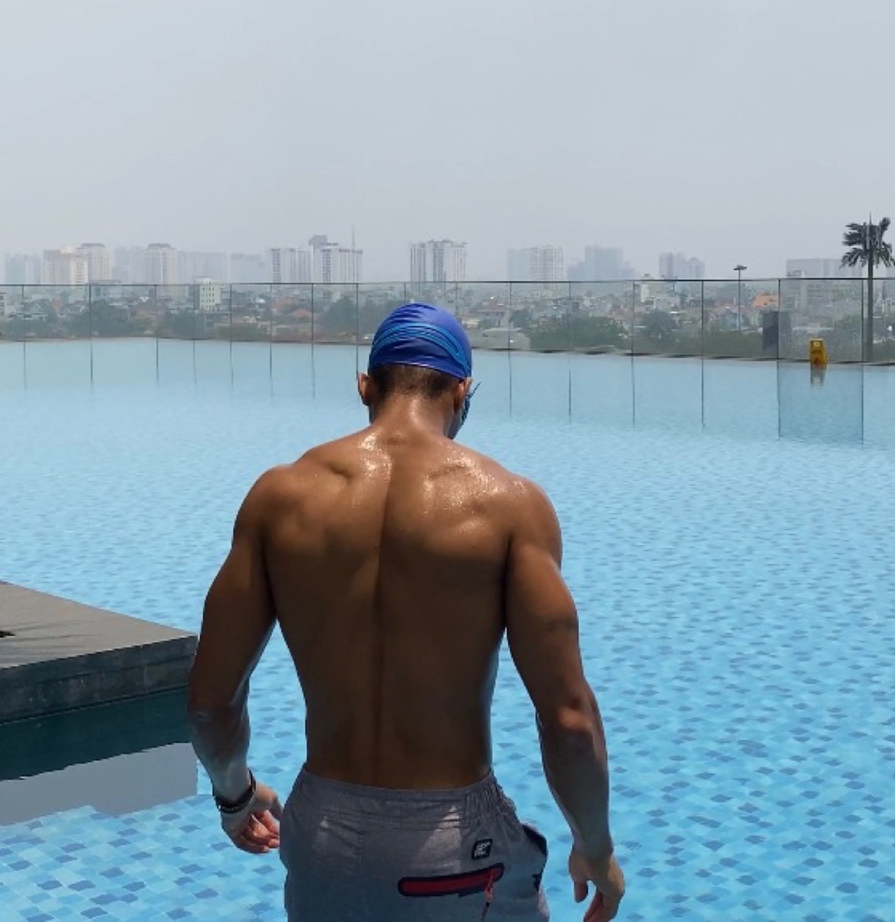 OYOTTA standing beside a rooftop pool and city skyline